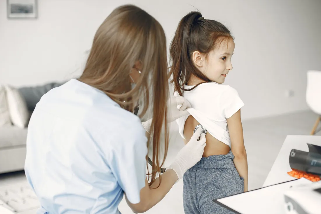 Médica examinando uma menina com estetoscópio em consulta